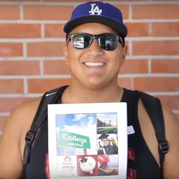 An Elite Community Scholars student holding a college guide